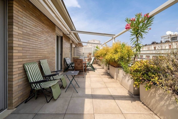 A balcony with a tiled floor, two striped chairs, a small table, and potted plants. - [Glamorous Terrace] Excl. 3bdr at 300mt from Central (Milan)