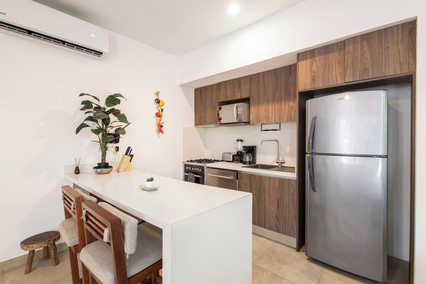 Une cuisine moderne dotée d’un îlot central, de meubles en bois, d’un réfrigérateur en acier inoxydable et d’une cuisinière encastrée.