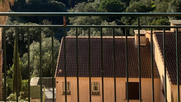 Uma varanda com vista para o mar, casas e vegetação.