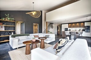 Un salon moderne comprenant un canapé, une table basse et un coin repas avec des chaises.