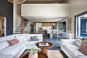 A modern living room with a sectional sofa, a coffee table, and a view into the kitchen area.
