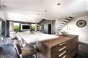 Une cuisine moderne dotée d’un grand îlot central, de tabourets de bar, d’un four encastré et d’un escalier au design original.