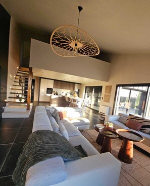 A spacious living area with a large sofa, a coffee table, and a unique ceiling light fixture.