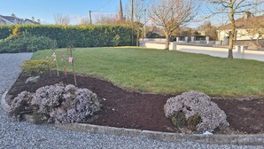 Un jardín ajardinado con un césped bien cuidado, arbustos florecientes y un sendero de grava.