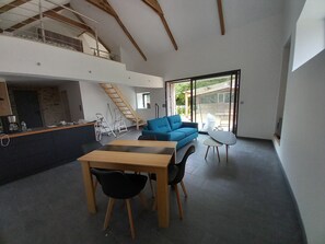 Un intérieur moderne comprenant un coin repas, un canapé bleu et un escalier menant à un niveau supérieur.