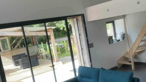 Een moderne woonkamer met een blauwe bank, een klein rond tafeltje en een trap naar een hoger gelegen verdieping.