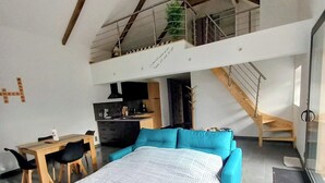 Een moderne loft slaapkamer met een groot bed, een eethoek en een keuken.