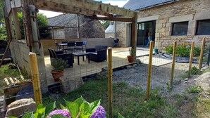 Een patio met buitenmeubilair, een pergola en een stenen gebouw op de achtergrond.