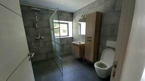 Een moderne badkamer met een douchecabine van glas, een toilet en een wastafel met spiegel.