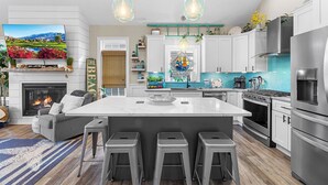 Una cocina moderna con una isla grande, electrodomésticos de acero inoxidable e iluminación colgante.