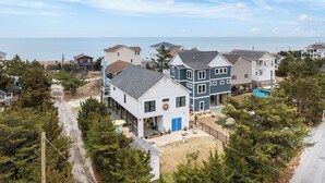 Un área residencial costera con casas, un sendero de arena y vista al mar.