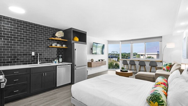 Una habitación de hotel moderna con cocina, una cama grande, un sofá y vistas al exterior.