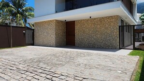 Une maison moderne à deux étages, dotée d’une façade en pierre, d’une allée pavée et d’une clôture en métal noir.