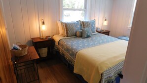 A bedroom with a bed, bedside tables, a nightstand, a window, and an air conditioning unit. - Sweet cottage nestled in scenic Drummer's Cove (CS0052) (Wellfleet)