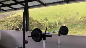 Un espacio de gimnasio techado al aire libre con una prensa de banca y barra.