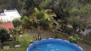 Una piscina elevada redonda, con escalera, rodeada de césped y árboles pequeños.