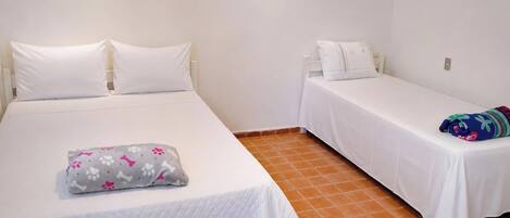 A room with two beds, each with white bedding and pillows.