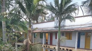 A two-story building with a white facade, multiple doors, and a balcony. - Pousada das Cores Cocais (Cocais)