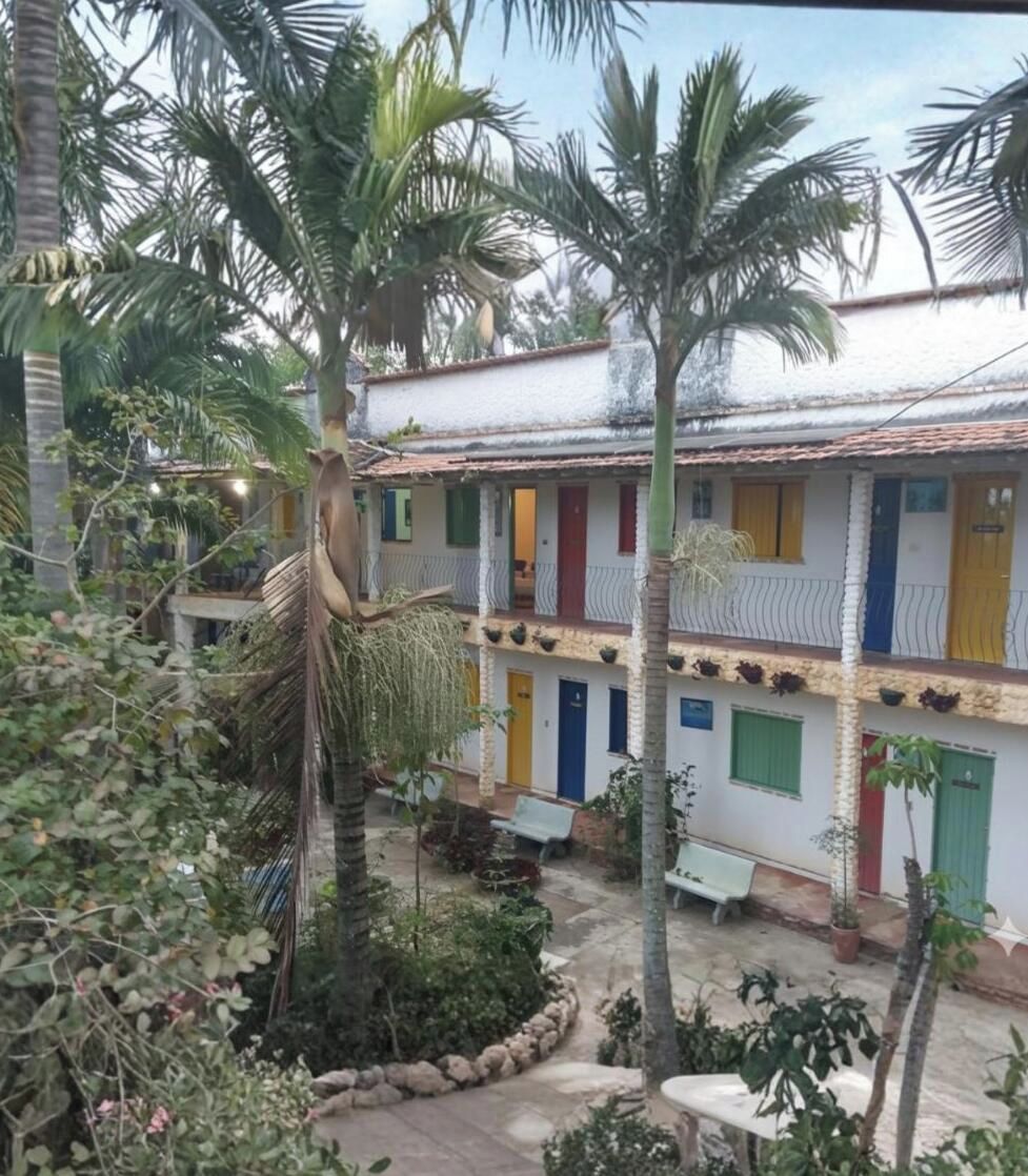 Um edifício de dois andares com fachada branca, várias portas e uma varanda.