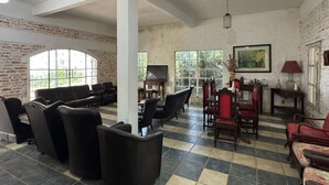 A spacious room with a checkered floor, a large window, and a television. - Pousada das Cores Cocais (Cocais)