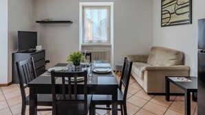 Ruokailutila, jossa on kahdelle katettu pöytä, televisio ja patteri.