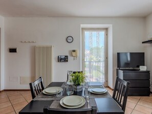 Ein Essbereich mit einem Tisch für vier Personen, einer Uhr, einem Thermostat und einem Fernseher auf einem Schrank.