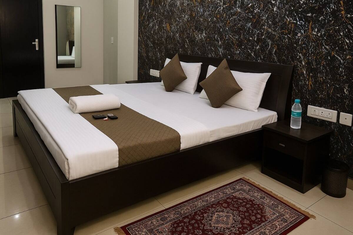 Ein modernes Hotelzimmer mit einem großen Bett, einem Nachttisch, einem Spiegel und einer Marmorwand.