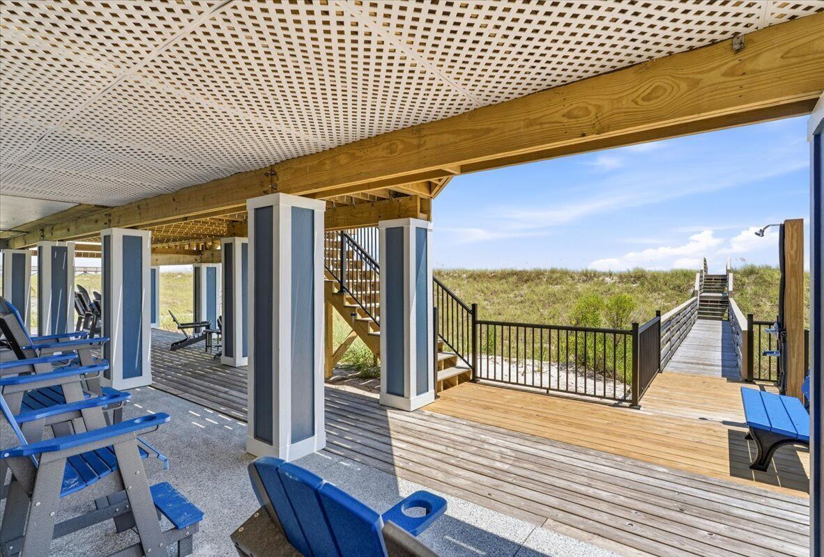 Een overdekt buitengebied met een houten terras, blauwe banken en een trap die naar een hoger niveau leidt.