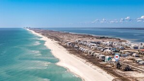 An aerial view of a coastal area with a beach, buildings, and a marina.