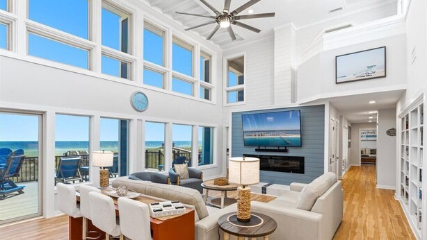 A spacious living area with a large TV, seating, and a view of the ocean.