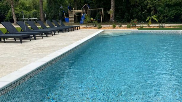 A swimming pool with a tiled edge, surrounded by lounge chairs and a small slide. - The Oasis Gardens, Beautiful House (Barry-d'Islemade)