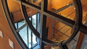 A circular window with a metal frame, wooden beams, and a view of the interior space below. - La Vert-Dîne (Saint-Pardoux)