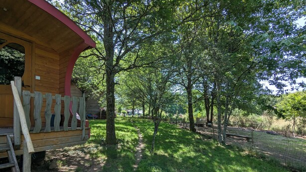 A wooden cabin with a red roof, surrounded by a fenced garden with trees and a clear path. - La Vert-Dîne (Saint-Pardoux)