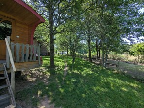 A wooden cabin with a red roof, surrounded by a fenced garden with trees and a clear path. - La Vert-Dîne (Saint-Pardoux)