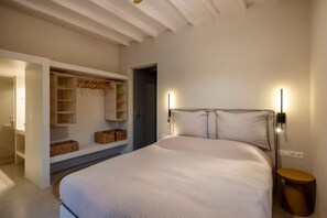 A bedroom with a large bed, built-in shelving, and a bedside table. - Modern Village House in Paros with Jacuzzi close to the Sea (Paros)