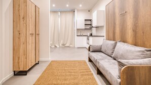 Ein modernes Wohnzimmer mit einer Couch, einem Holzschrank und einer Küche im Hintergrund.