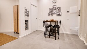 Ein kleiner Essbereich mit Tisch und Stühlen, einer Uhr an der Wand und einer Tür zu einem anderen Raum.