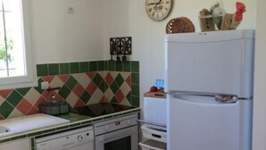A kitchen with a dishwasher, oven, and refrigerator. There is a window with a view of greenery outside.