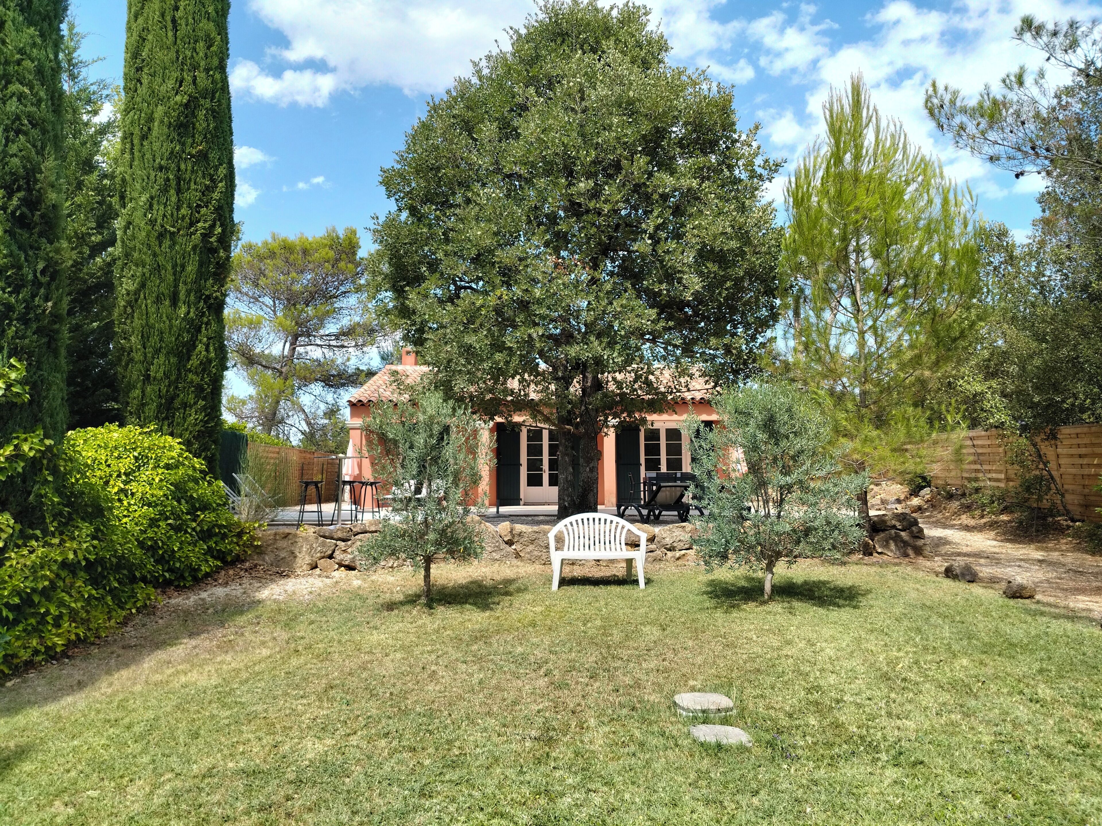 A house with a patio, surrounded by a well-maintained lawn and various trees.