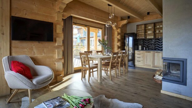 A wooden interior with a dining area, a flat-screen TV mounted on the wall, and a fireplace. - Comfortable Holiday Villa With Mountain Views (Zakopane)