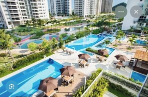 Ein Poolbereich auf dem Dach mit mehreren Schwimmbecken, Liegestühlen und Sonnenschirmen.