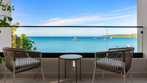 A balcony with two wicker chairs and a small table, overlooking a calm sea with boats and a distant shoreline. - Beachfront Modern Villa with Pool | Azure (Punta Rucia)