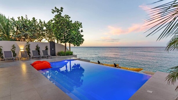 A swimming pool with a view of the sea, lounge chairs, and a sunset. - Beachfront Modern Villa with Pool | Azure (Punta Rucia)