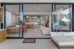 Een modern interieur met een keuken, een eethoek en een woongedeelte, met schuifdeuren en een welkomstmat.