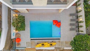 An aerial view of a modern pool area with a glass enclosure, seating, and kayaks. - Beachfront Modern Villa with Pool | Azure (Punta Rucia)