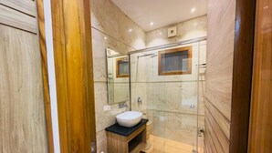 A modern bathroom with a glass-enclosed shower, a white sink, and a wooden vanity. - Hotel Silver Bricks (Amritsar)