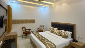 A modern bedroom with a large bed, a ceiling fan, and a desk with a chair. - Hotel Silver Bricks (Amritsar)