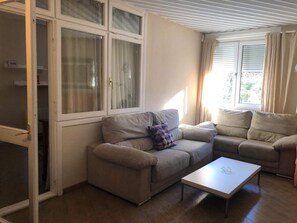 A living room with two sofas, a coffee table, and a sliding glass door leading to a balcony. - Warm Sierra Nevada Apartment for 8 (Monachil)