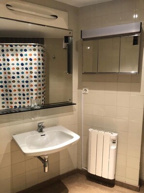 A bathroom with a white sink, a mirror, a shower curtain with colorful polka dots, and a white radiator. - Warm Sierra Nevada Apartment for 8 (Monachil)