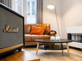 A modern living room with a vintage Marshall speaker, a brown leather sofa, a small round coffee table, and a floor lamp.